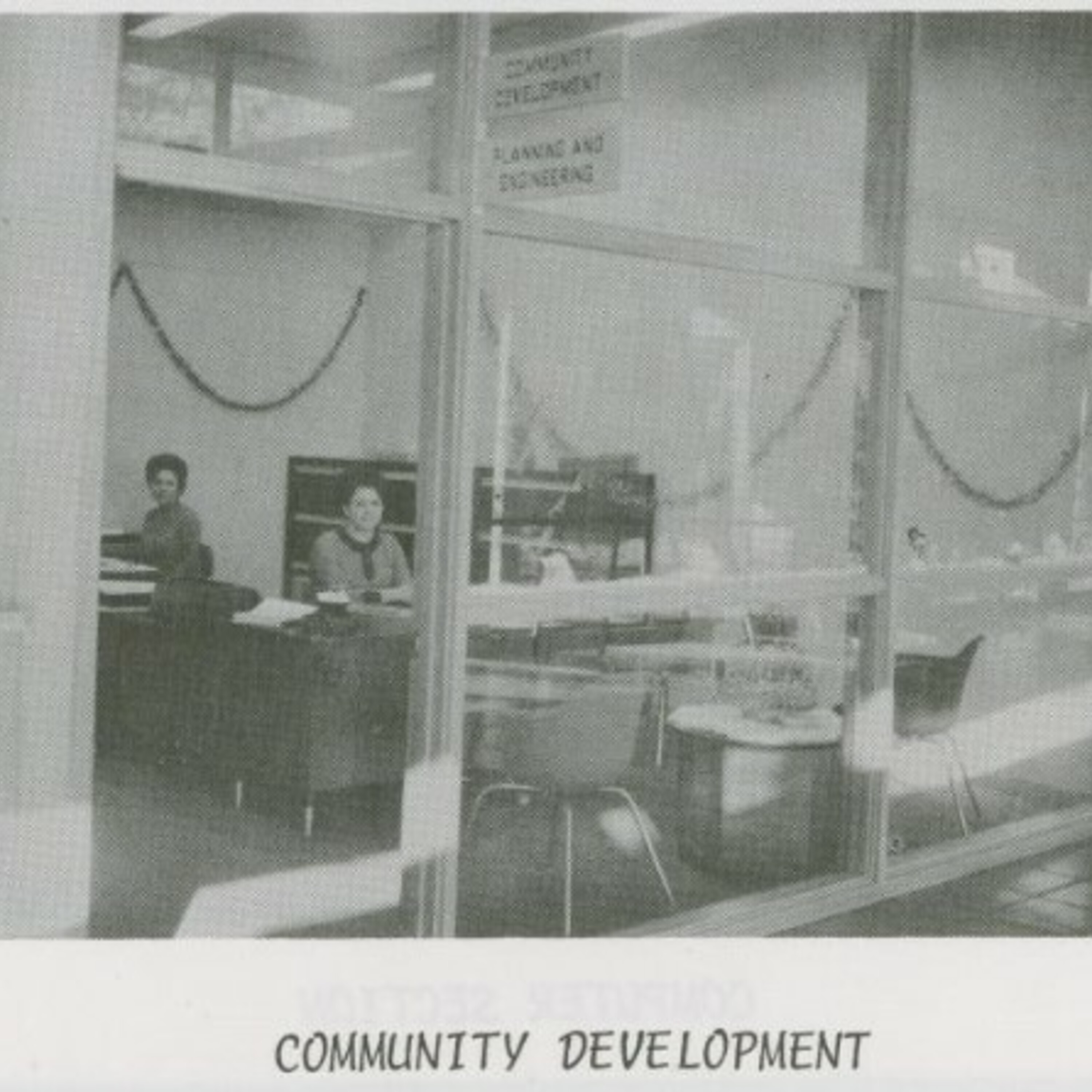 Two unknown women are seated at desks inside the Community Development room in Denton City Hall. The photo appears in the December 1969 city employee newsletter, The Spotlight.