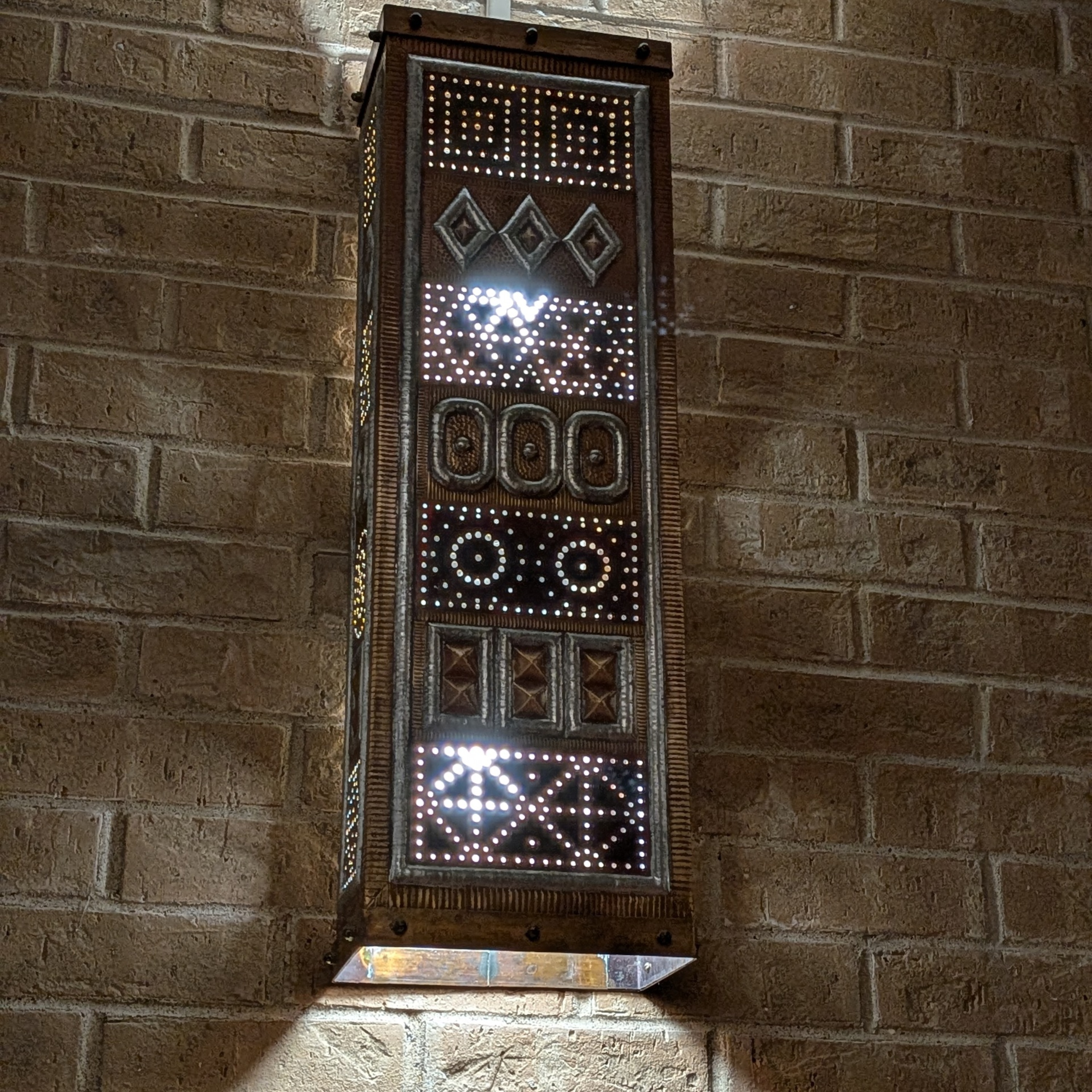 This handmade brass and tin light is shining brightly on a cloudy day inside Denton City Hall. 
