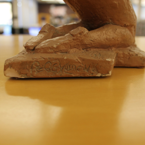 This close-up of the "Play Time" sculpture shows the name 'Peggy Mach' crudely etched into the base near the woman's right foot.